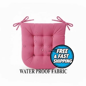 May include: A pink, square seat cushion with a tufted design and attached ties. The cushion is made of water-resistant fabric, with water droplets visible on the surface. The cushion is designed for outdoor or indoor use.
