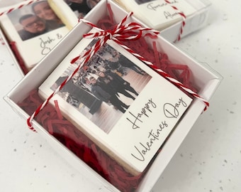May include: Three clear boxes with red and white string bows contain personalized photo cookies. The cookies are decorated with photos and text. The text on the cookies reads "Josh & Ch", "Forever and Always", and "Happy Valentines Day".
