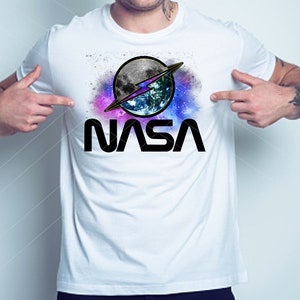May include: White t-shirt with a graphic of a stylised NASA logo featuring a blue and green Earth with a lightning bolt and a moon in a galaxy background. The text "NASA" is printed in black below the graphic.