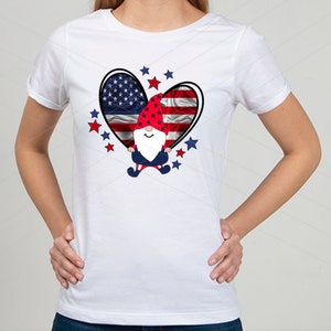 May include: White t-shirt with a red, white, and blue heart design featuring a gnome wearing a red and white hat. The heart is surrounded by red and blue stars.