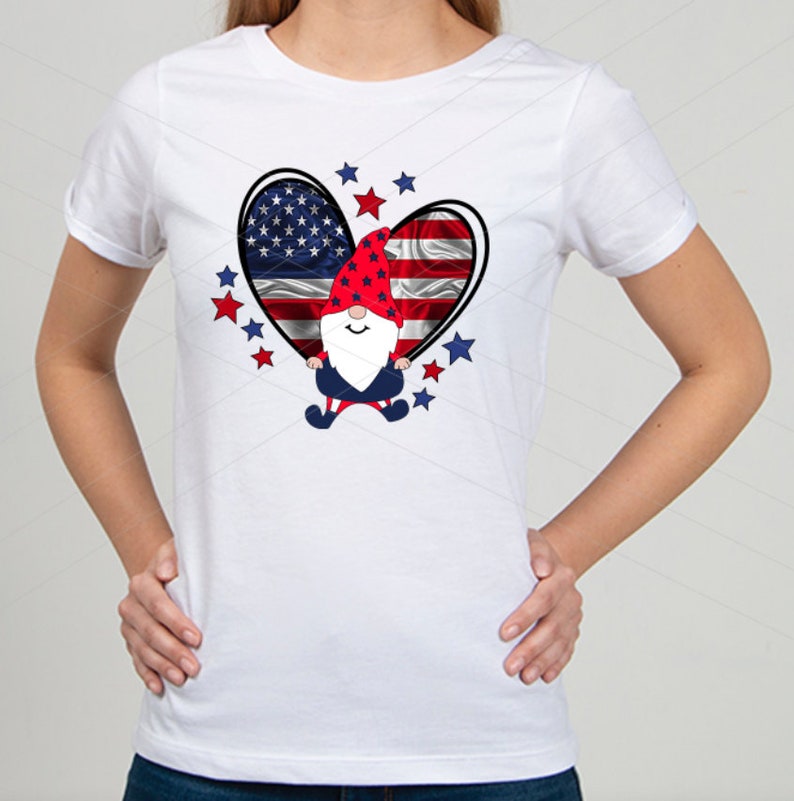May include: White t-shirt with a red, white, and blue heart design featuring a gnome wearing a red and white hat. The heart is surrounded by red and blue stars.