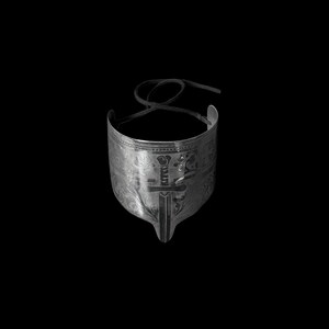May include: A silver-toned metal cuff bracelet with intricate engraved patterns and a sword design. The bracelet has a curved shape and a black cord for closure, set against a black background.