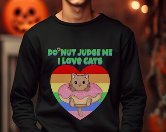 May include: Black sweatshirt with a rainbow heart design and a cat inside a donut. The text on the sweatshirt reads "Do Nut Judge Me I Love Cats".