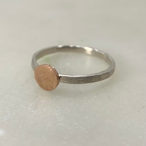 May include: A silver ring with a round, textured, rose gold accent.
