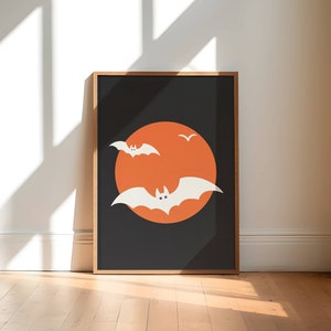 A framed picture of white bats flying over an orange moon.