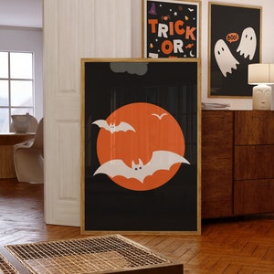 A gallery wall set of 3 framed Halloween artworks in orange, black and white color schemes.