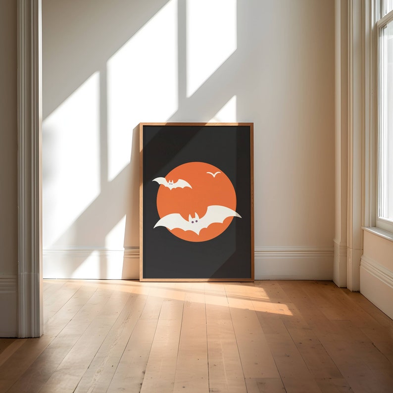 A framed picture of white bats flying over an orange moon.