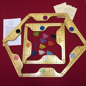 May include: A wooden cribbage board game set with a red felt background. The board is made of light wood and has a hexagonal shape. The set includes pegs in various colors, including blue, red, green, yellow, and white. The board has a total of 120 holes for the pegs. The set also includes instructions for playing the game.
