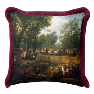 May include: A square decorative cushion featuring a printed scene of a historical hunting party with horses, hounds, and a carriage in a forest setting. The cushion is bordered by a deep burgundy ruffled fabric trim and has a visible zipper.