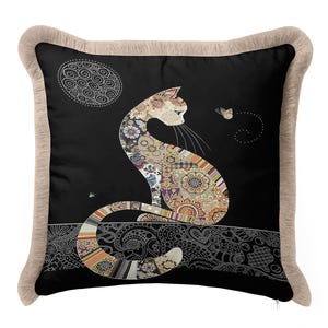 Può includere: Un cuscino quadrato con sfondo nero e bordo a frange beige. Il centro presenta l'illustrazione di un gatto composta da motivi floreali e geometrici colorati, seduto sopra un bordo a linee bianche con una farfalla e una luna.