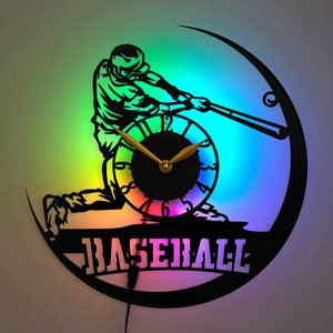 May include: A black vinyl record clock with a silhouette of a baseball player swinging a bat. The clock face is a rainbow of colors and the words "BASEBALL" are printed below the player.