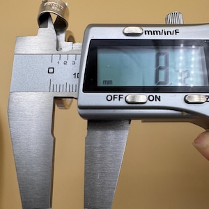 Puede incluir: Un anillo de plata se est&aacute; midiendo con un calibre digital. El calibre lee 8,12 mm.