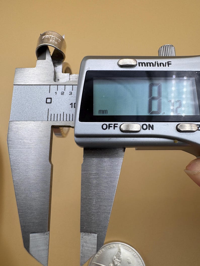 Puede incluir: Un anillo de plata se est&aacute; midiendo con un calibre digital. El calibre lee 8,12 mm.