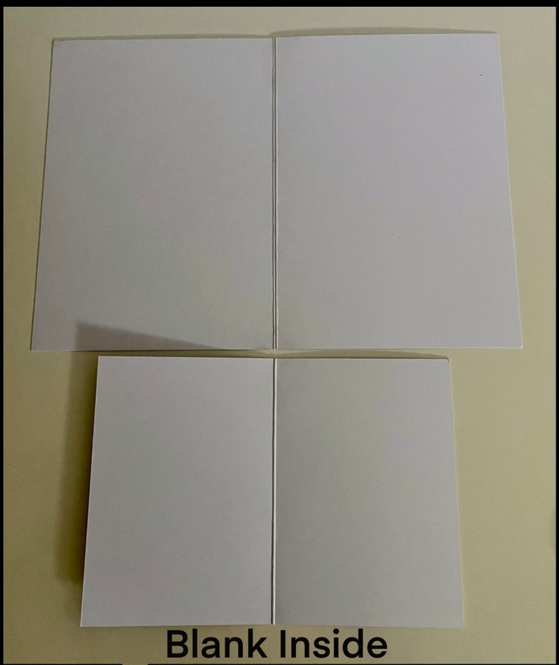 May include: Two blank white greeting cards folded in half. The cards are stacked on top of each other. The text "Blank Inside" is printed below the cards.