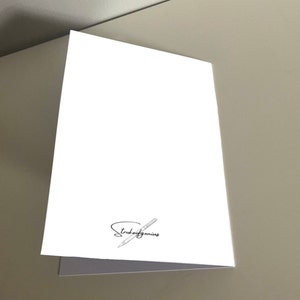 May include: Blank white card with a pen and the text "Stroke of Genius" in black.