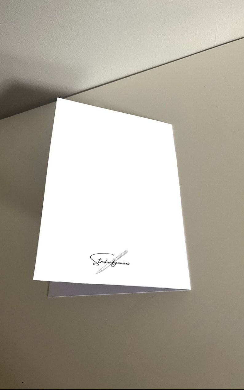May include: Blank white card with a pen and the text "Stroke of Genius" in black.