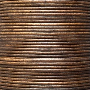 May include: Close-up of a spool of brown leather cord. The cord is tightly wound, creating a textured surface with visible horizontal lines. The leather has a natural, aged appearance with variations in colour.