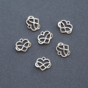 May include: Six silver infinity heart charms, each with a delicate, intertwined design. These charms are perfect for adding a touch of love and eternity to jewellery projects.