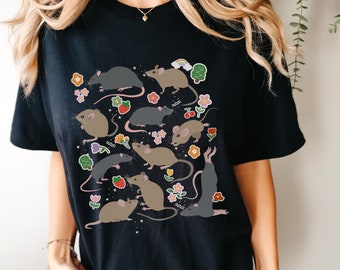 Könnte beinhalten: Schwarzes T-Shirt mit einem grafischen Druck von mehreren Comic-Mäusen und Blumen. Die Mäuse sind in verschiedenen Posen und Farben dargestellt, darunter grau, braun und weiß.