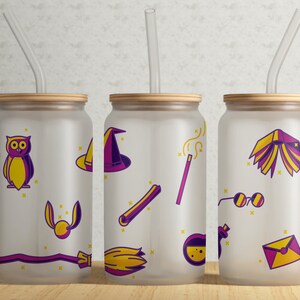 Puede incluir: Tres vasos de vidrio esmerilado con tapas de madera y pajitas transparentes. Cada vaso presenta un diseño diferente de Harry Potter en morado y amarillo. Los diseños incluyen un sombrero de mago, una varita mágica, un libro, una snitch dorada, un búho y un par de gafas.