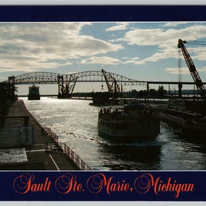 May include: A vintage postcard featuring the Sault Ste. Marie, Michigan, waterway. The image shows a large bridge, a boat, and industrial cranes under a cloudy sky. The text "Sault Ste. Marie, Michigan" is at the bottom.