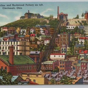 May include: Vintage postcard featuring a colorful cityscape of Cincinnati, Ohio, with the Mt. Adams Incline and Rockwood Pottery. Buildings of various sizes and colors are nestled on a hillside, with the text "Mt. Adams Incline and Rockwood Pottery on left. Cincinnati, Ohio" at the top.
