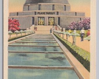 May include: Vintage postcard featuring the Adler Planetarium and Terrazzo Promenade in Chicago. The image shows the planetarium with a large dome, a long walkway, and reflecting pools. The sky is a light blue, and the postcard has a cream-colored border.