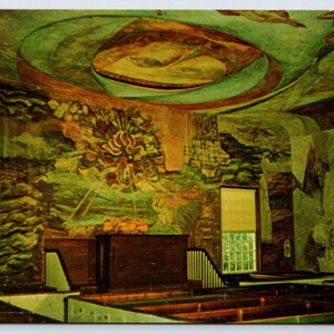 May include: A large, colorful mural depicting a scene of people and animals, painted on the ceiling of a room with wooden pews. The mural is painted in shades of green, brown, and blue.