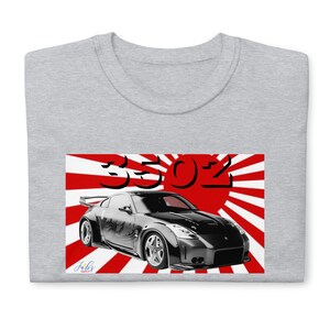 May include: A light gray t-shirt featuring a graphic of a black sports car with the text "350Z" in black. The car graphic is set against a red and white background, with the artist's signature in the lower left corner.