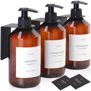 May include: Three amber glass bottles with black pump tops and white labels. The labels read "FINESSY SHAMPOO SHAMPOING 17 oz | 500 ml", "FINESSY CONDITIONER APRES SHAMPOING 17 oz | 500 ml", and "FINESSY SHOWER GEL GEL DOUCHE 17 oz | 500 ml".