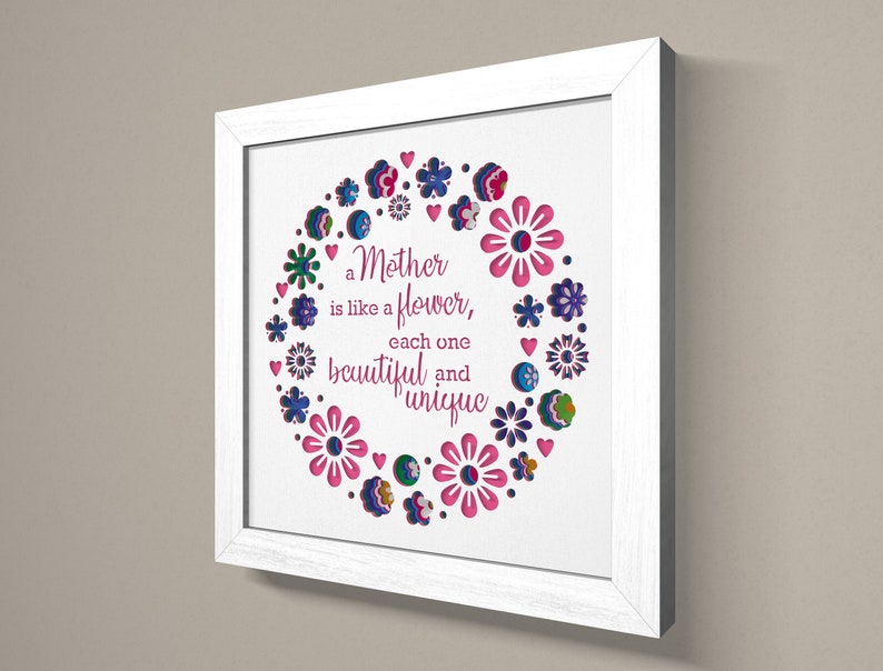 May include: White framed wall art with a pink, blue, and green floral design. The text reads "a Mother is like a flower, each one beautiful and unique".