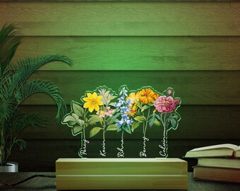 May include: A wooden base with five floral designs, each with a name underneath: Percy, Kevin, Rhina, Benny, and Calvin. The floral designs are illuminated with a green light.