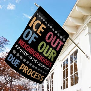 May include: Black flag with the text "ICE OUT OF OUR NEIGHBORHOODS FREEDOM REQUIRES DUE PROCESS" in various colors. The flag is hanging from a white house with a blue sky background.