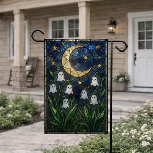 May include: A rectangular garden flag featuring a stained glass style illustration of a crescent moon and yellow stars against a dark blue night sky, with several small white ghost figures emerging from green leafy plants at the bottom.