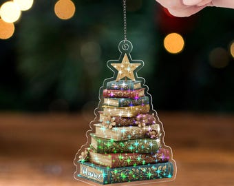 May include: Clear acrylic Christmas tree ornament shaped like a stack of books, topped with a star. The books are in shades of green, red, and gold, with intricate designs. The text "Name" is at the bottom, and "ACRYLIC - TWINKLE" is at the bottom right.
