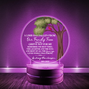 May include: A purple illuminated acrylic plaque with a wooden base. The plaque features a tree with a red bird and the text "A limb has fallen from our family tree that say grieve not for me remember the best times, the laughter and the song and most of all the good life I lived while I was strong. Andrey Henderson 1974-2023".