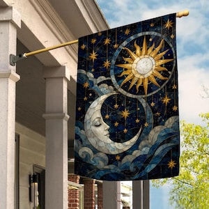 May include: A rectangular garden flag featuring a stained glass style design of a golden sun and a white crescent moon with a face. The background is a deep blue night sky filled with golden stars and swirling blue clouds, all suspended from a pole.