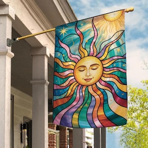May include: A colorful outdoor flag featuring a smiling sun with closed eyes. The sun has a yellow face and radiating rays in shades of orange, red, blue, and purple. The background is a mix of blue and teal with stars.