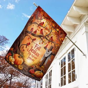 May include: A decorative outdoor flag featuring a fall scene with pumpkins, a cross, and red cardinals perched in a tree. The flag has the text "Fall for Jesus He never leaves" in red script.