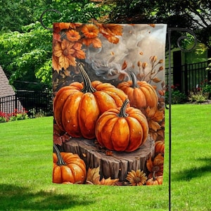 May include: A decorative garden flag featuring a vibrant autumn scene. The flag showcases several orange pumpkins on a wooden stump, surrounded by fall foliage in shades of orange and brown. The background has a smoky effect.