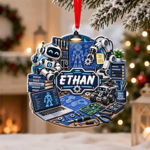 May include: A flat, circular ornament featuring a white robot holding a screwdriver, a robotic arm, a laptop displaying code, and various tools. The center displays the name ETHAN in bold white letters against a blue background with gear motifs.