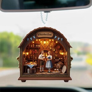 May include: A hanging car ornament shaped like a wooden tavern interior with the text Oktoberfest. The scene features two figures in traditional clothing holding beer mugs, surrounded by miniature kitchenware, a wooden barrel, and warm lighting.