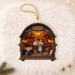 May include: A brown, arched, hanging ornament featuring a detailed 3D diorama of an Oktoberfest scene. Inside, two figures in traditional attire hold beer steins within a rustic tavern setting, complete with miniature shelves, barrels, and lights.