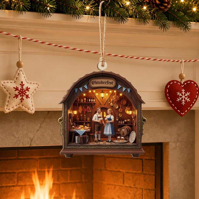 May include: A brown, arched, hanging ornament featuring a detailed 3D diorama of an Oktoberfest scene. Inside, two figures stand in a tavern with wooden walls, shelves of bottles, hanging kitchen tools, and a table with food, illuminated by warm lights.