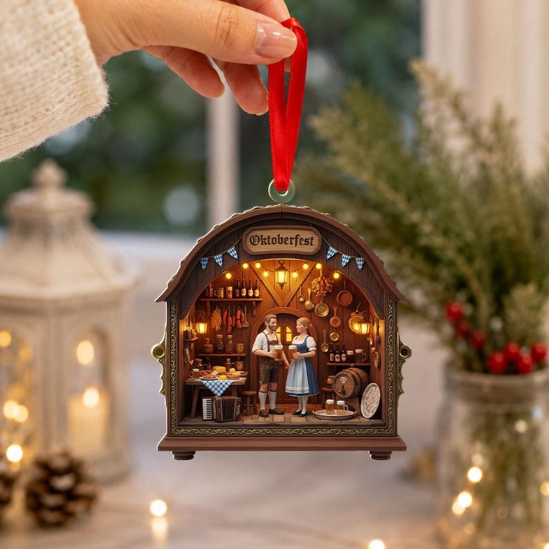May include: A decorative hanging ornament shaped like a wooden archway with the text Oktoberfest. The interior scene depicts two figures in traditional clothing standing in a tavern with shelves, hanging kitchenware, and warm glowing lights.