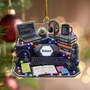 May include: A decorative acrylic ornament featuring a computer workstation with a laptop displaying code, a keyboard, a mouse, headphones, a stack of books labeled System Design, Clean Code, Algorithms, and Data Structures, and a mug reading Code. Build. Repeat.