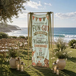 May include: A vertical banner on a gold metal stand featuring light green stripes, bunting, and woodland animals. The text reads: A LITTLE FUN-GUY IS ON THE WAY WELCOME TO Nathan's BABY SHOWER SEP 15 2026. It includes illustrations of a deer, bear, and mushrooms.