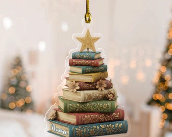 May include: A Christmas tree ornament shaped like a stack of books, topped with a star. The books are in various colors, including blue, green, and red, with floral designs. The word "Name" is written on the bottom book.