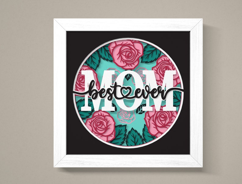 May include: White framed art print with a black background and a circle in the centre. The circle has a turquoise background with pink roses and green leaves. The text "MOM best ever" is in white with a pink heart in the middle of the word "best".
