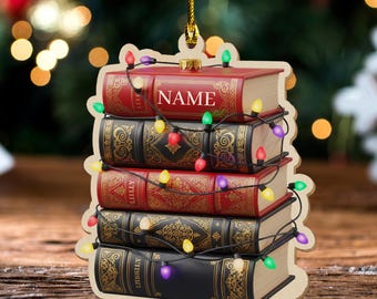 May include: A wooden Christmas ornament shaped like a stack of books. The books are red and black with gold accents, strung with colorful lights. The top book has the word "NAME" printed on it.